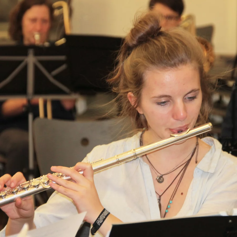 Eine junge Frau sitzt in einem Orchester und spielt Querflöte 