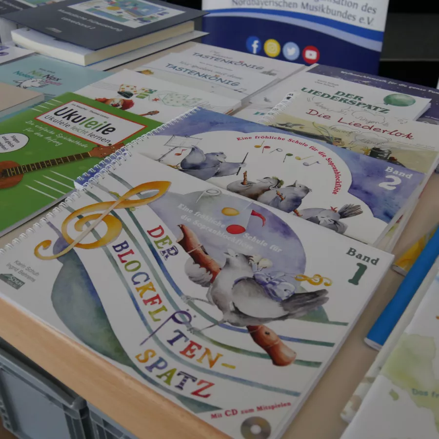 Auf einem Tisch liegen viele verschiedene Bücher zur musikalischen Früherziehung. 