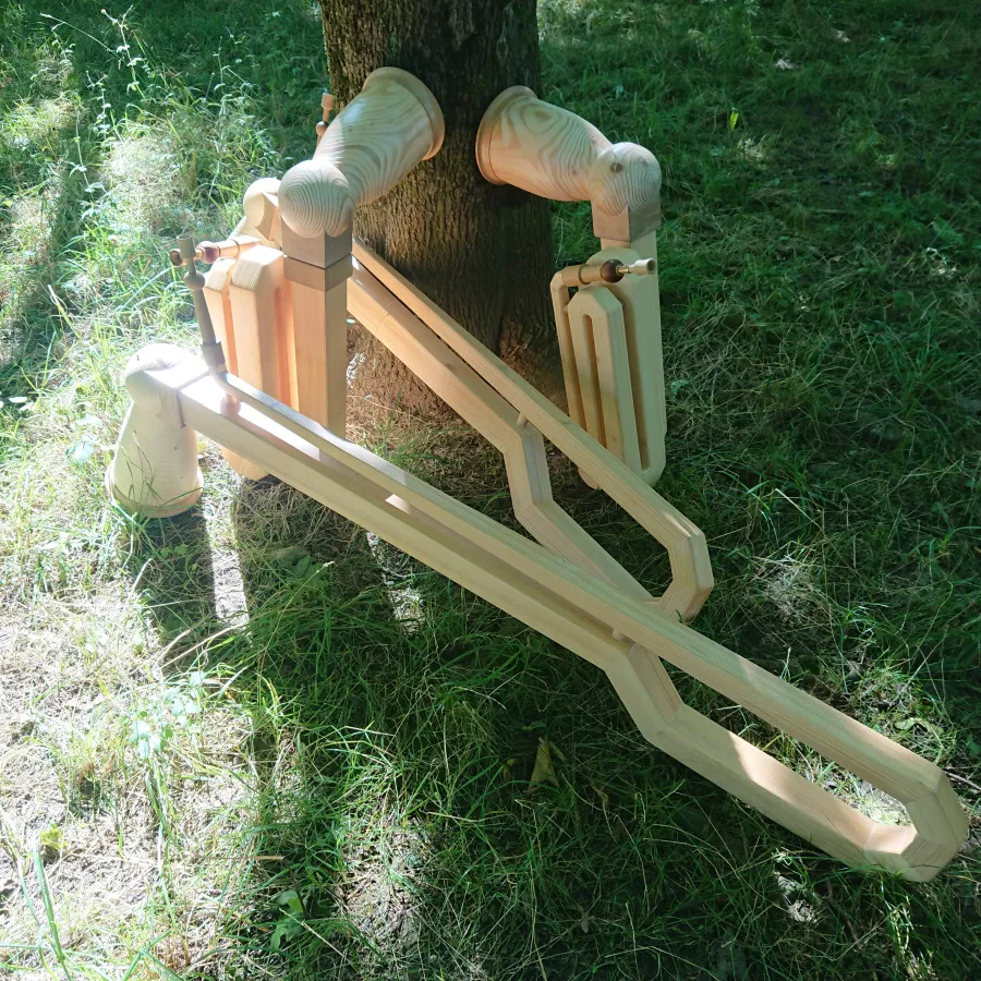 Zwei Vogelhörner und zwei Kompakthörner aus Holz lehnen an einem Baum auf einer Wiese. 