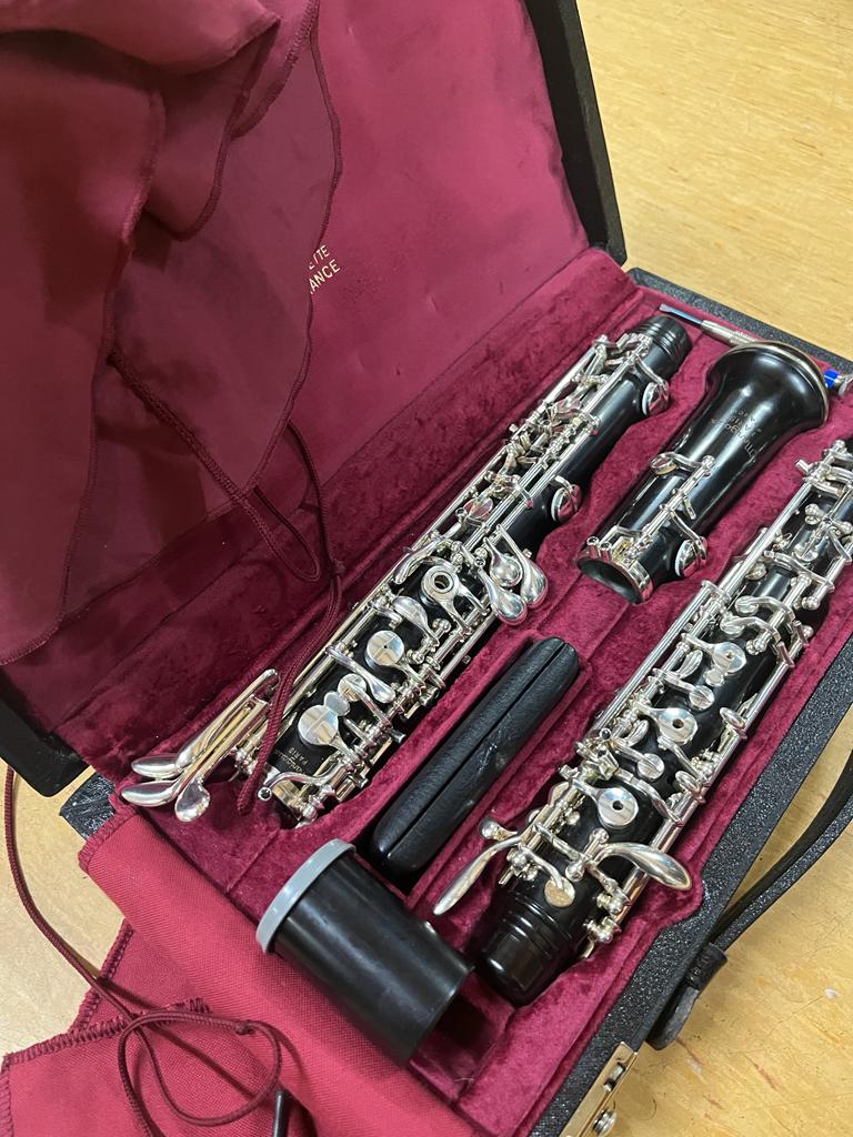 Eine Oboe ist auseinandergebaut und liegt in einem Instrumentenkoffer, der mit rotem Samt ausgekleidet ist. 