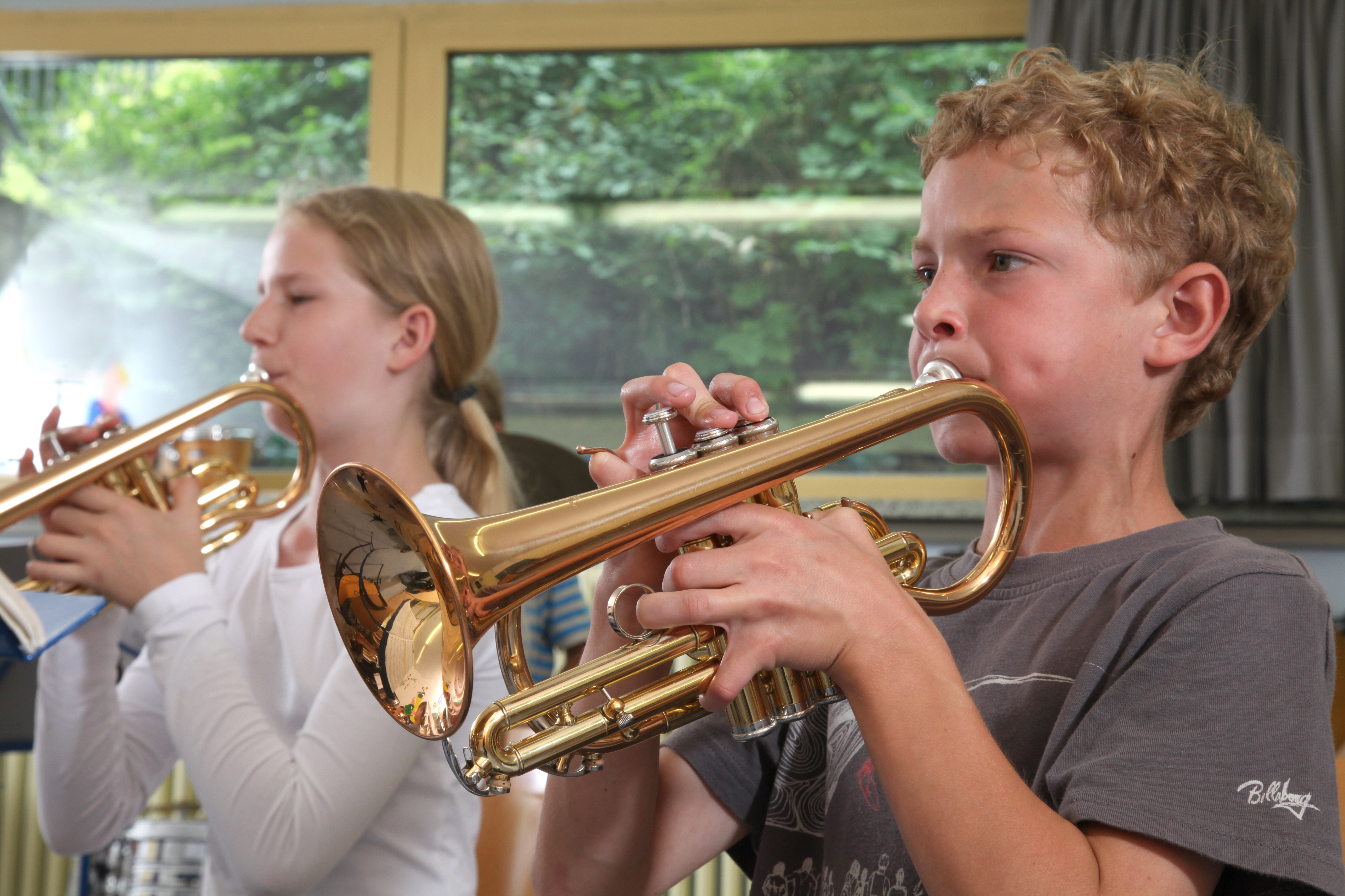 Ein Mädchen und ein Junge spielen gemeinsam Trompete.