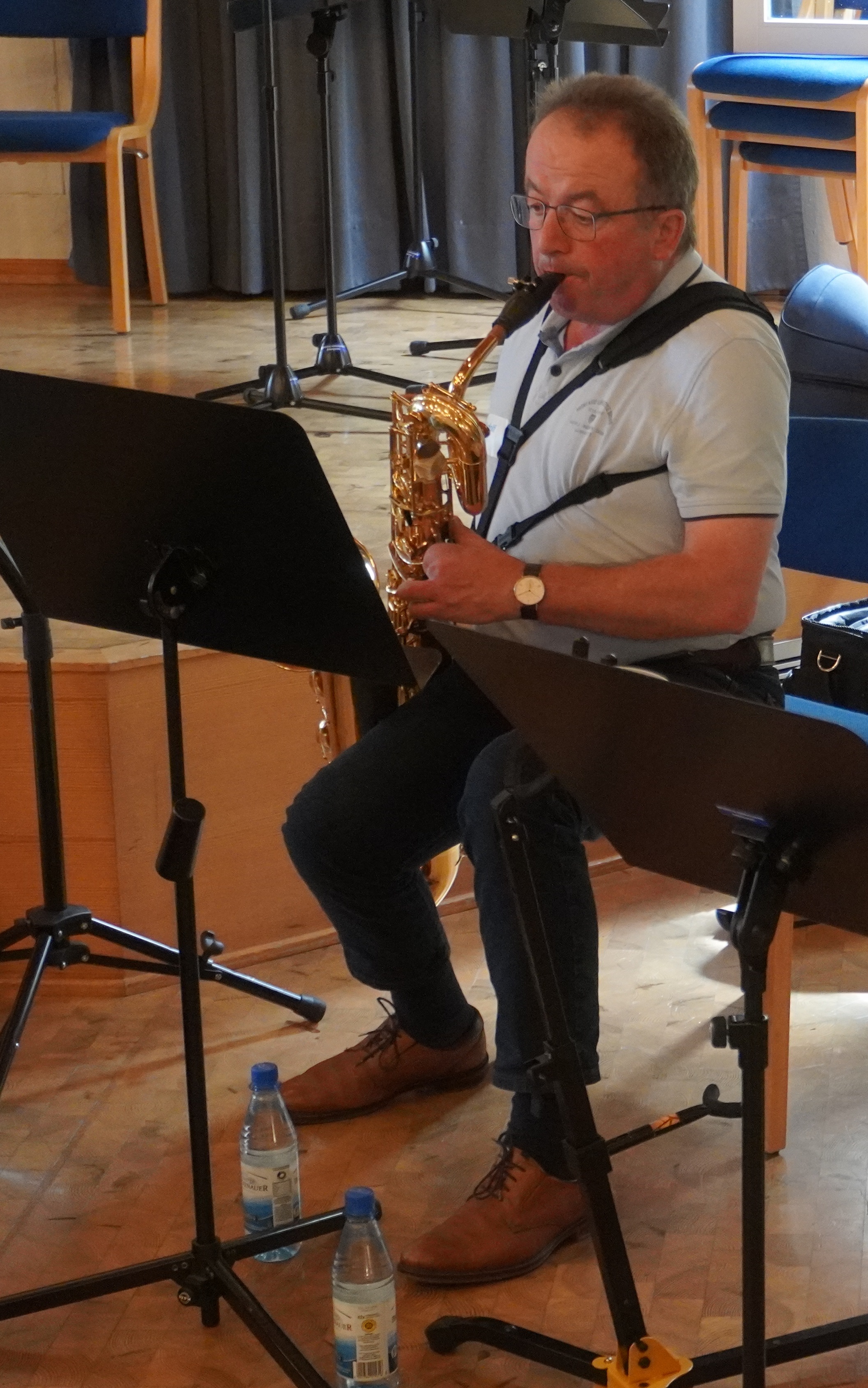 Ein Mann sitzt in einem Raum. Er spielt auf einem Saxophon.