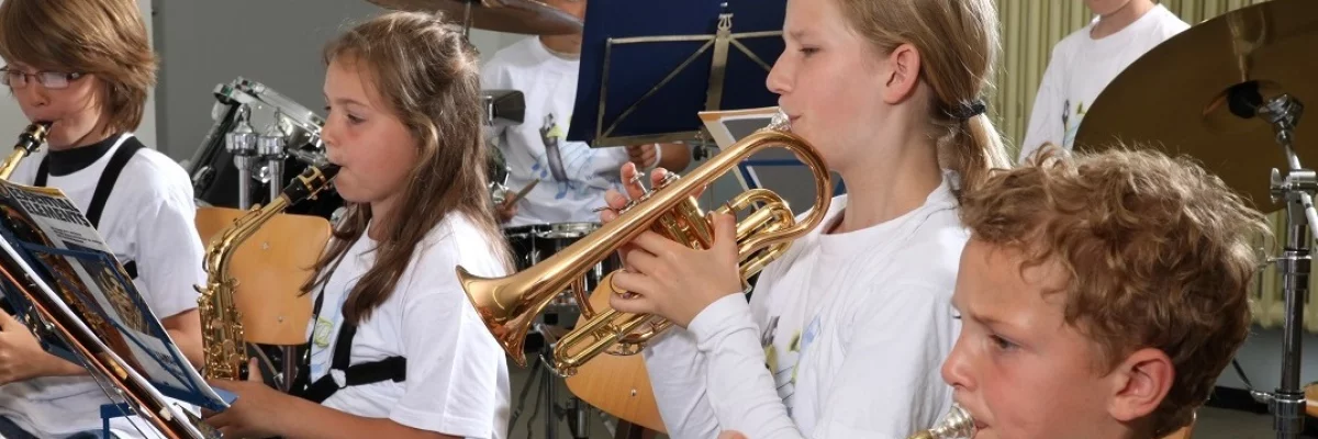 Kinder musizieren auf verschiedenen Instrumenten gemeinsam. 