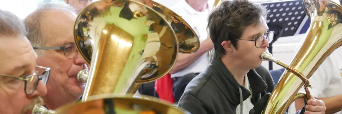 Ein Junge mit Down-Syndrom sitzt in einem Blasorchester und spielt Tenorhorn. 