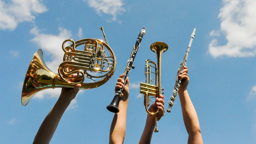 Vier Blasinstrumente werden in den blauen Himmel gehalten. 