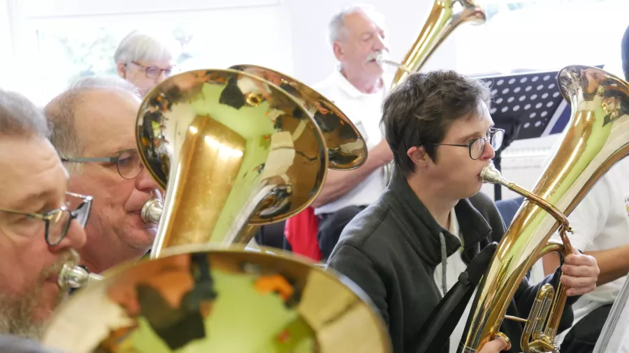 Ein Junge mit Down-Syndrom sitzt in einem Blasorchester und spielt Tenorhorn. 
