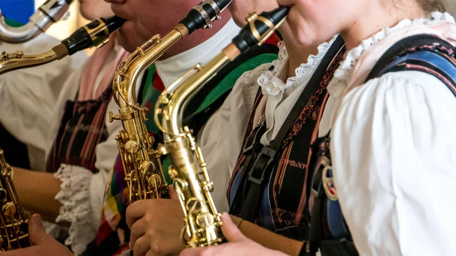Mehrere Menschen spielen in Tracht Saxophon.